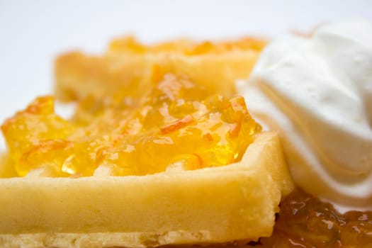 Toasted waffles with orange jam and cream on top.