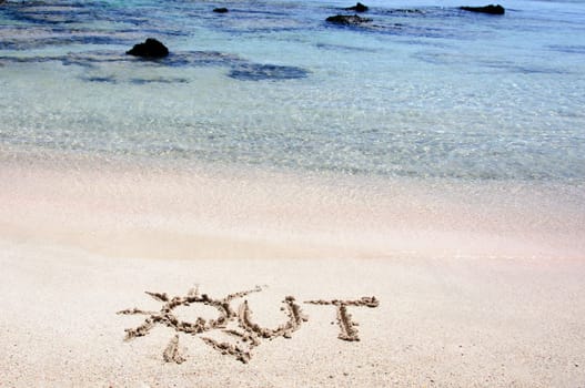 Word "OUT"" written on sand on a beautiful beach, blue waves in background"
