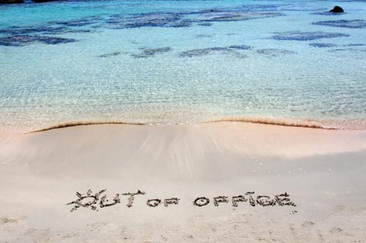 OUT OF OFFICE written on sand on a beautiful beach, blue waves in background .Relax concept image