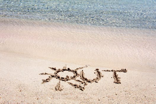 Word "OUT"" written on sand on a beautiful beach, blue waves in background"