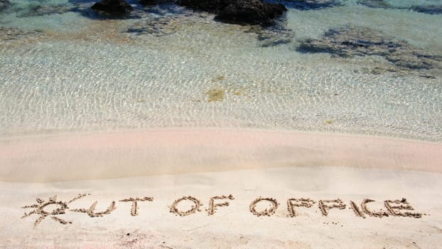 OUT OF OFFICE written on sand on a beautiful beach, blue waves in background .Relax concept image