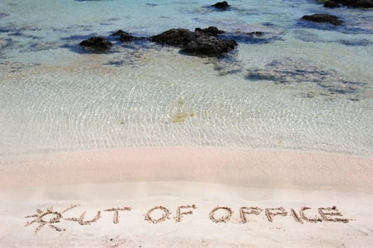 OUT OF OFFICE written on sand on a beautiful beach, blue waves in background .Relax concept image