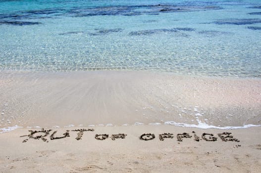 OUT OF OFFICE written on sand on a beautiful beach, blue waves in background .Relax concept image
