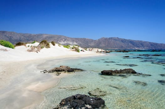 Elafonisi or Elafonissi, "deer island"" in Greek, is an island located close to the southwestern corner of the Mediterranean island of Crete, Greece. Elafonisi is an oblong, which often ""breaks"" in two parts by water giving the impression of being a separate island. The island is a protected nature reserve."
