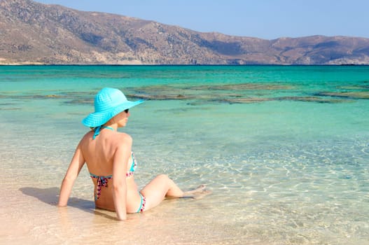 Beautiful young woman in bikini with sunhat, relaxing on the sunny beach. Relaxing concept
