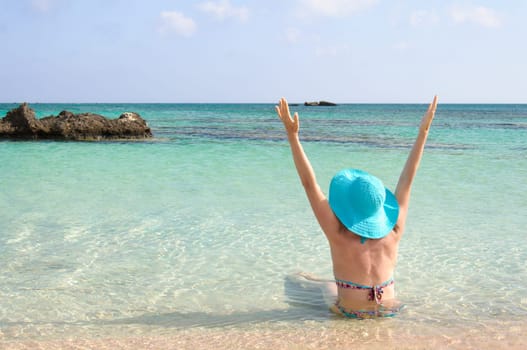 Beautiful young woman in bikini with sunhat, relaxing on the sunny beach. Relaxing concept