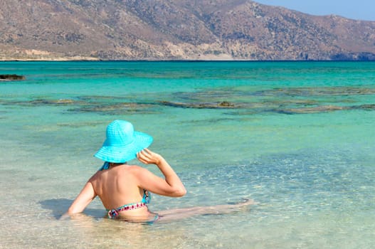 Beautiful young woman in bikini with sunhat, relaxing on the sunny beach. Relaxing concept