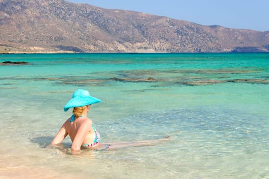 Beautiful young woman in bikini with sunhat, relaxing on the sunny beach. Relaxing concept