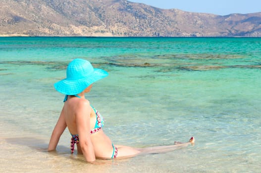 Beautiful young woman in bikini with sunhat, relaxing on the sunny beach. Relaxing concept