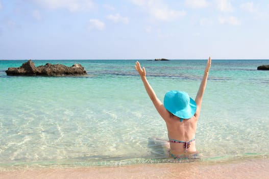 Beautiful young woman in bikini with sunhat, relaxing on the sunny beach. Relaxing concept