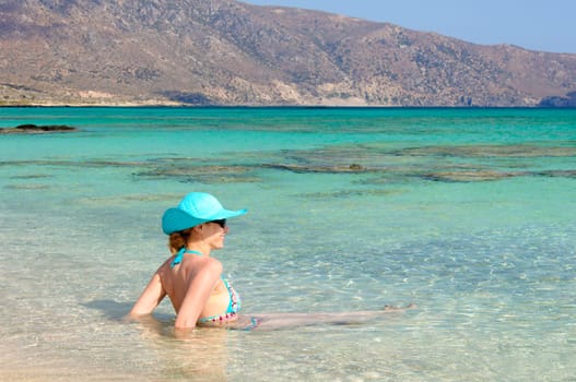 Beautiful young woman in bikini with sunhat, relaxing on the sunny beach. Relaxing concept