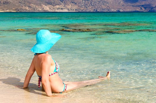 Beautiful young woman in bikini with sunhat, relaxing on the sunny beach. Relaxing concept