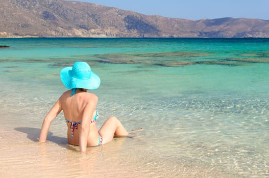 Beautiful young woman in bikini with sunhat, relaxing on the sunny beach. Relaxing concept