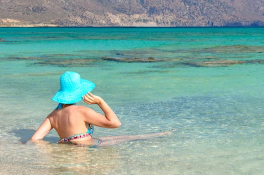 Beautiful young woman in bikini with sunhat, relaxing on the sunny beach. Relaxing concept