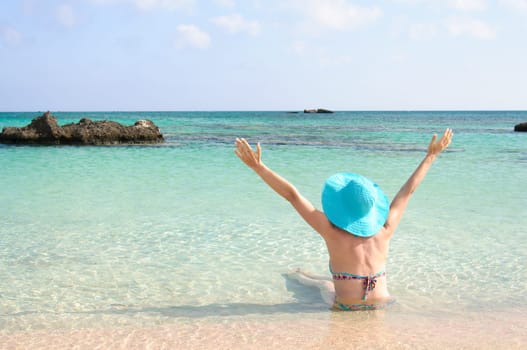 Beautiful young woman in bikini with sunhat, relaxing on the sunny beach. Relaxing concept