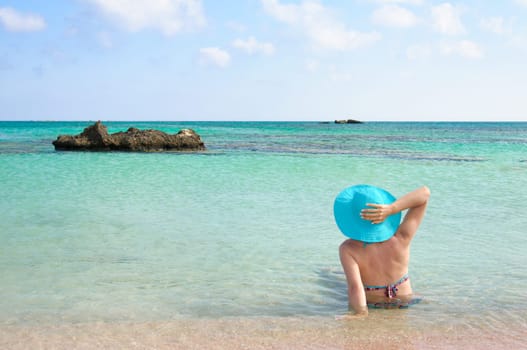 Beautiful young woman in bikini with sunhat, relaxing on the sunny beach. Relaxing concept