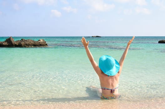 Beautiful young woman in bikini with sunhat, relaxing on the sunny beach. Relaxing concept