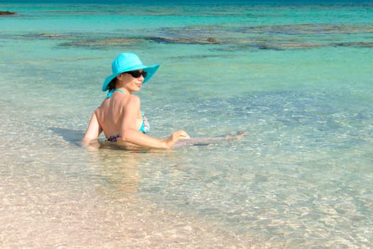 Beautiful young woman in bikini with sunhat, relaxing on the sunny beach. Relaxing concept