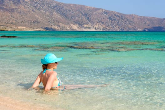 Beautiful young woman in bikini with sunhat, relaxing on the sunny beach. Relaxing concept