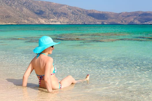 Beautiful young woman in bikini with sunhat, relaxing on the sunny beach. Relaxing concept