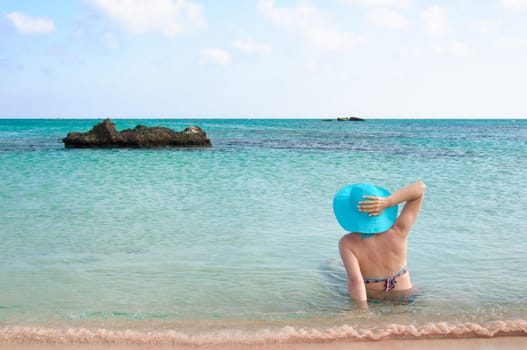 Beautiful young woman in bikini with sunhat, relaxing on the sunny beach. Relaxing concept