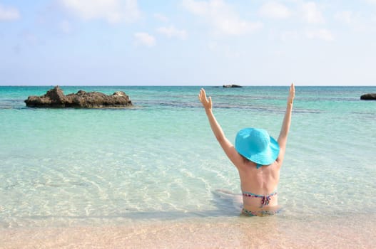 Beautiful young woman in bikini with sunhat, relaxing on the sunny beach. Relaxing concept