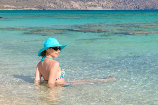 Beautiful young woman in bikini with sunhat, relaxing on the sunny beach. Relaxing concept