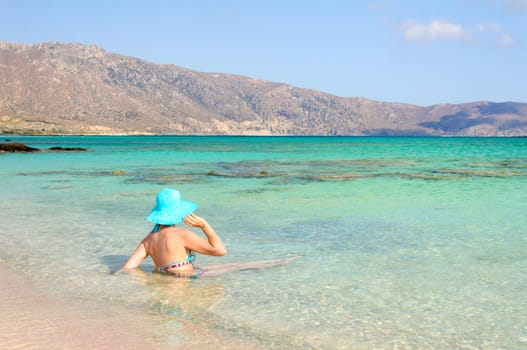 Beautiful young woman in bikini with sunhat, relaxing on the sunny beach. Relaxing concept