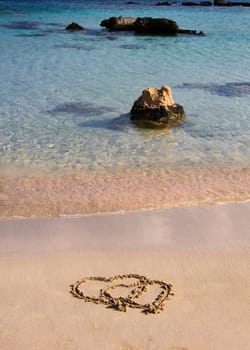 Two hearts drawn in the sand on a beautiful beach, with waves in background