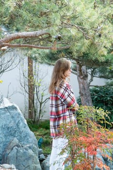 Woman in red plaid shirt enjoying nature standing in Japanese Garden