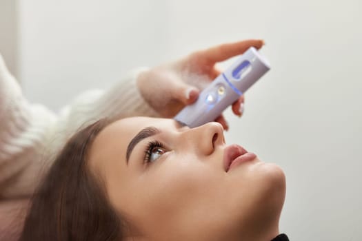 cosmetologist using primer spray for eyelash extension procedure in salon