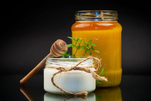 jar with natural homemade yogurt and delicious organic honey, isolated on a black background.