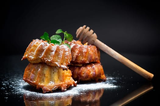 cooked sweet honey muffins in powdered sugar isolated on black background