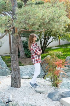 Woman in red plaid shirt enjoying nature standing in Japanese Garden