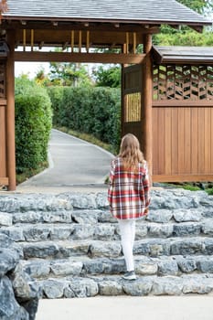 Woman in red plaid shirt enjoying nature walking in Japanese Garden