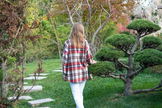 back view of Woman in red plaid shirt enjoying nature walking in Japanese Garden