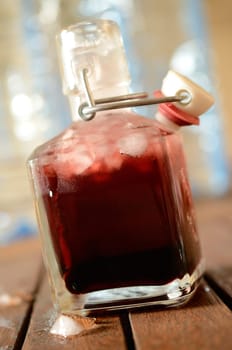 Cold bottle with juice of cherries and chrushed ice cubes