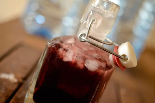 Cold bottle with juice of cherries and chrushed ice cubes