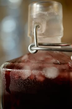 Cold bottle with juice of cherries and chrushed ice cubes