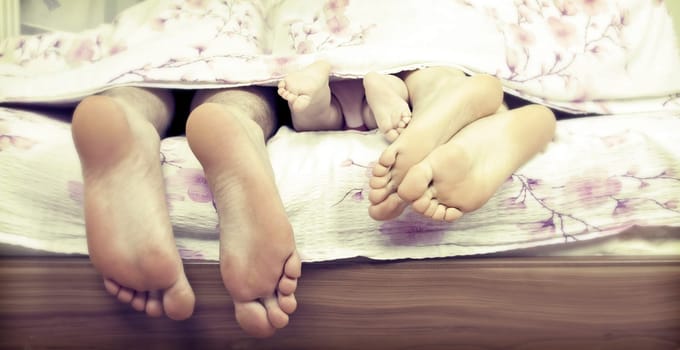 Tree pairs of legs - the happy family in bed