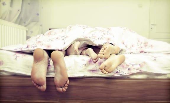 Tree pairs of legs - the happy family in bed