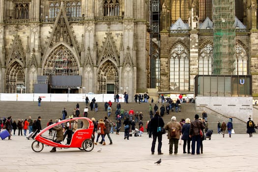 Cologne,Germany – January 02,2014: Tourists,travelers and a cycle rickshaw stand on the station forecourt in front of Cologne Cathedral on January 2,2014 in Cologne.