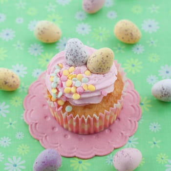 Small colorful cupcake with Easter eggs on a green background
