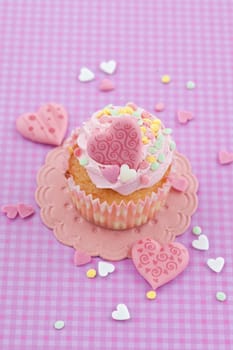 Small cupcake with colorful hearts on purple background