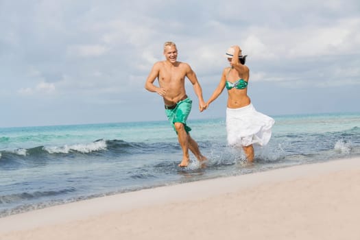 Young happy couple in love has fun on the beach in summer