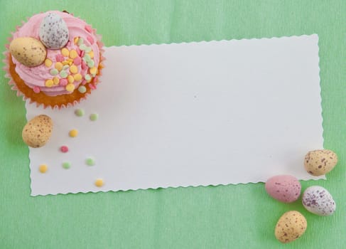 Small colorful cupcake with Easter eggs on a green background