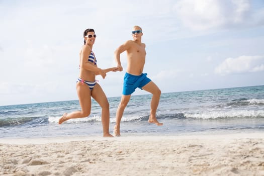 Young happy couple in love has fun on the beach in summer