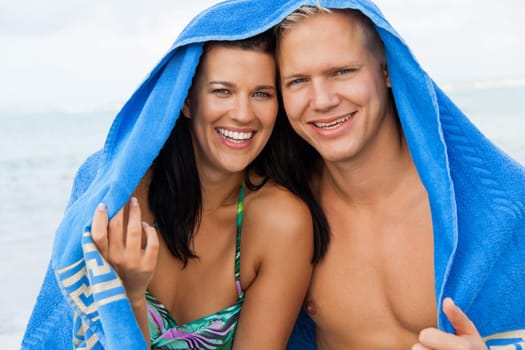 laughing young couple in love with a towel on the beach in summer holiday love leisure lifestyle