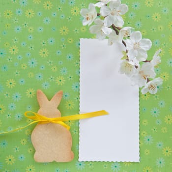 Colorful background with flowers and a cookie in the shape of an Easter bunny