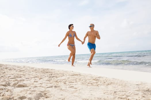 Young happy couple in love has fun on the beach in summer